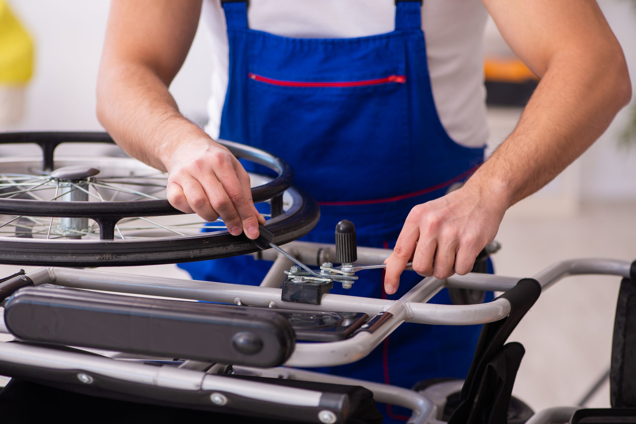 Young male repairer repairing wheel-chair indoors